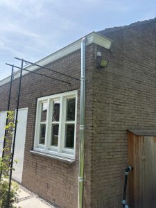 Nieuwe zinken regenpijp langs de gevel